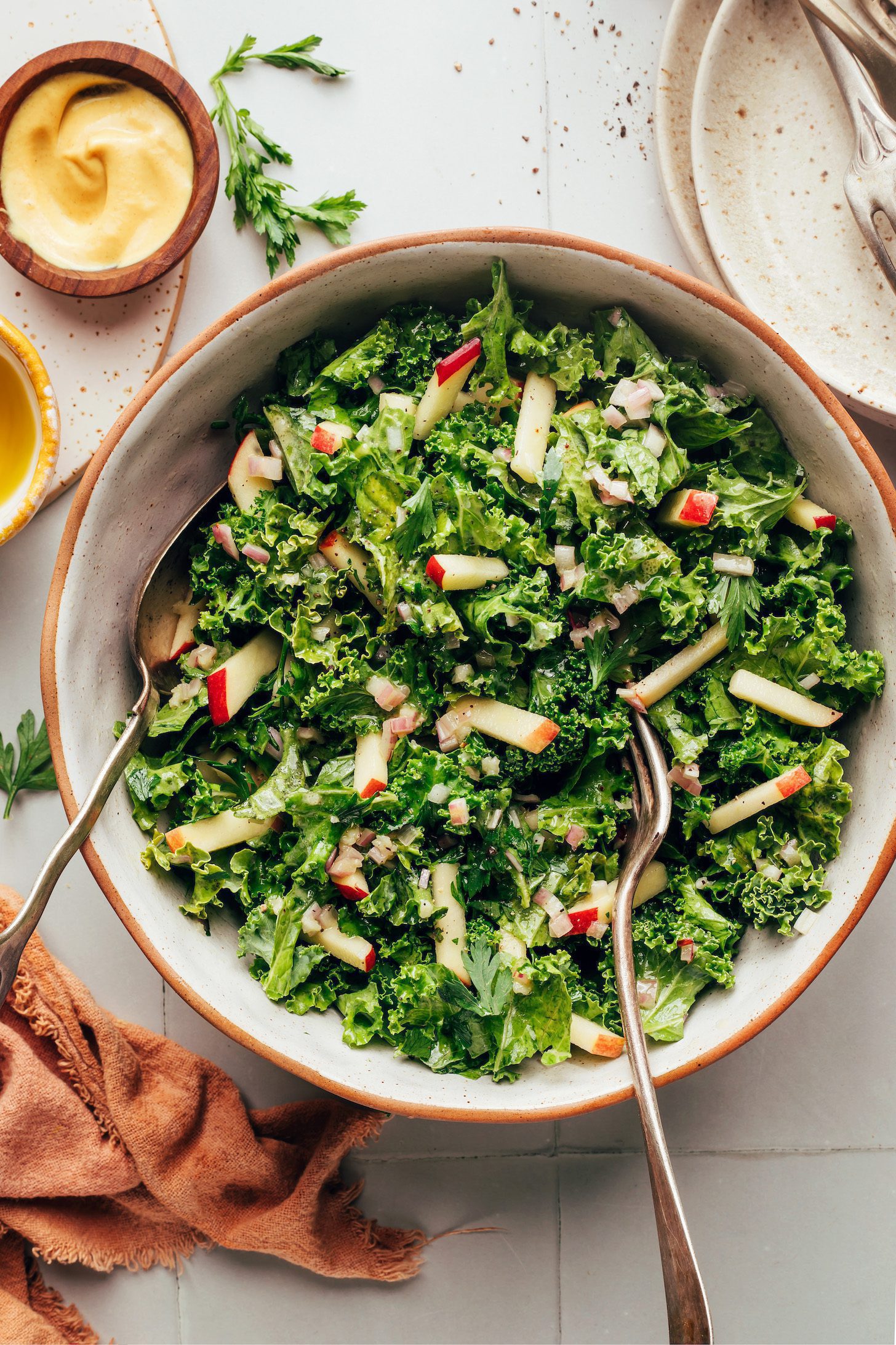 Serving utensils in a bowl of our simple kale apple slaw recipe